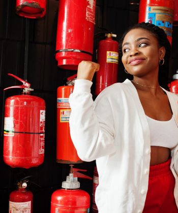 African woman posed against wall with old extinguisher.
